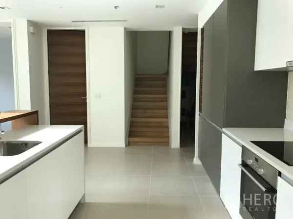 公寓 出租在Khlong San, Bangkok - 开放式厨房连接木楼梯，白色台面与高柜一体