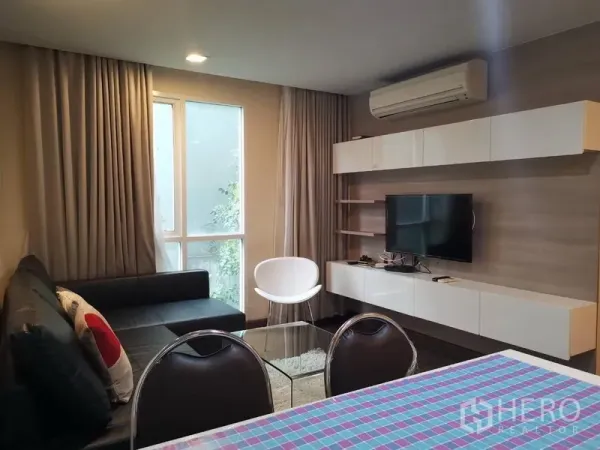 公寓 出租或出售在Watthana, Bangkok - 现代客厅，L形沙发、壁挂电视、悬空柜和大窗户的瓦他那公寓