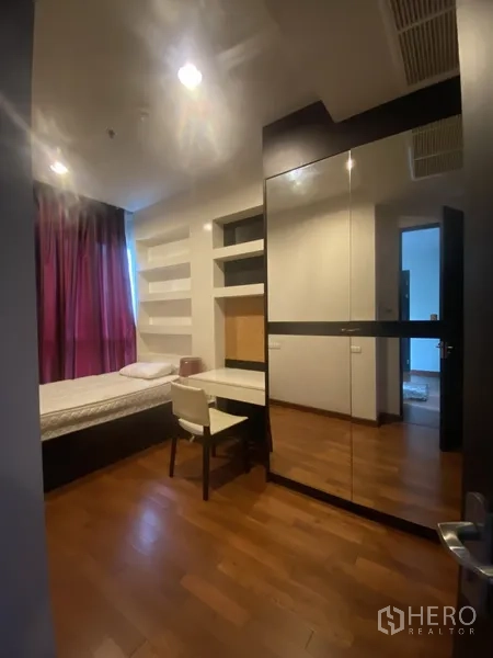 公寓 出租在Pathum Wan, Bangkok - 次卧带单人床、镜面衣柜、书桌与搁架，紫色窗帘。