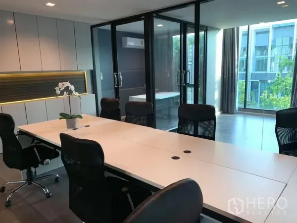 Home Office for rent - Conference room featuring a long white table, mesh chairs and glass partitions with natural light.