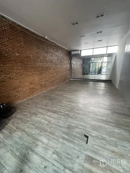零售空间 出租 - 开间式室内空间，砖纹特色墙与木纹地砖，后方有镜面。