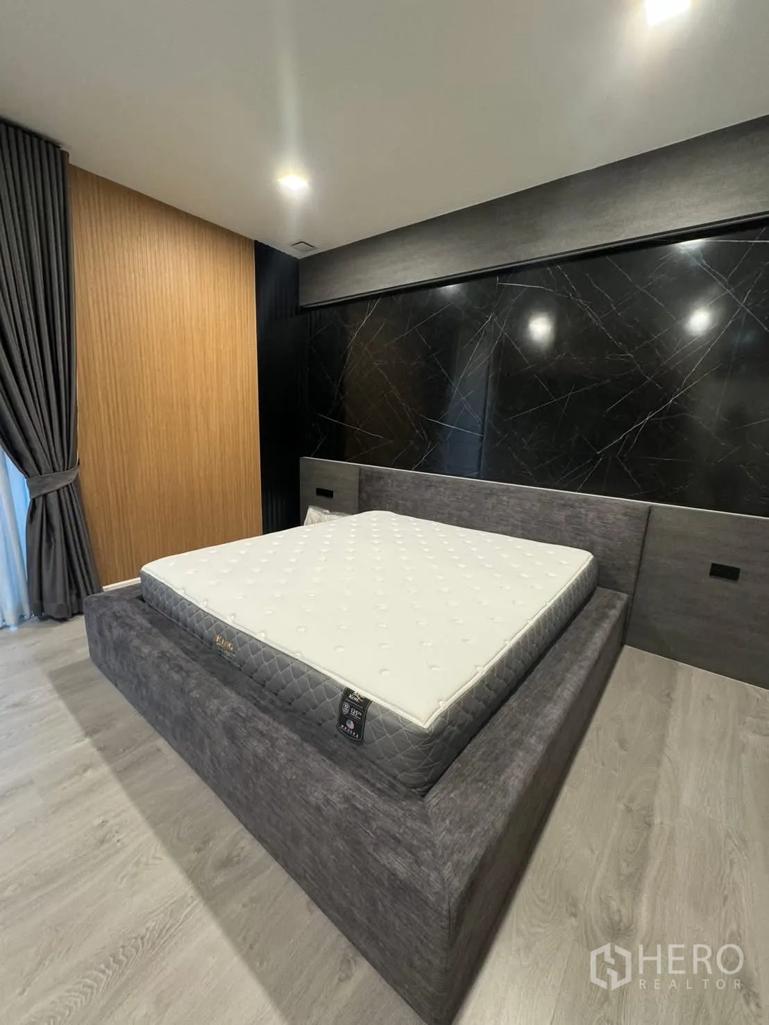 Detached House for rent in Prawet, Bangkok - Master bedroom with upholstered bed, black marble feature wall and wood accents.