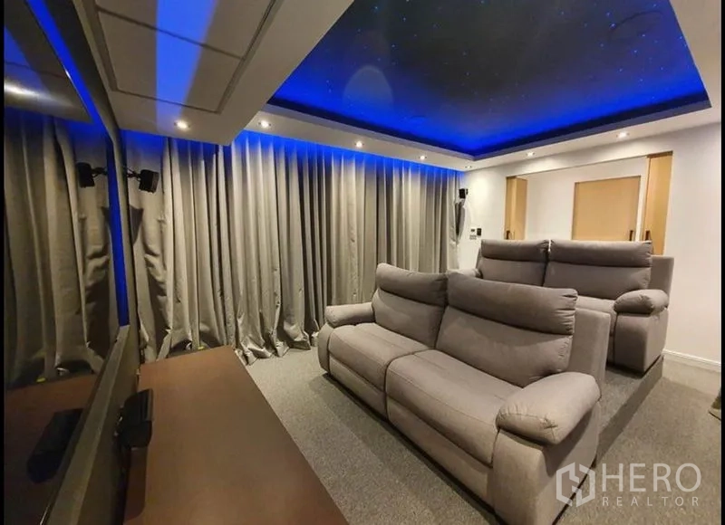 Condominium for rent in Watthana, Bangkok - Private home cinema with tiered recliners, starry ceiling and blue LED lighting, side view.
