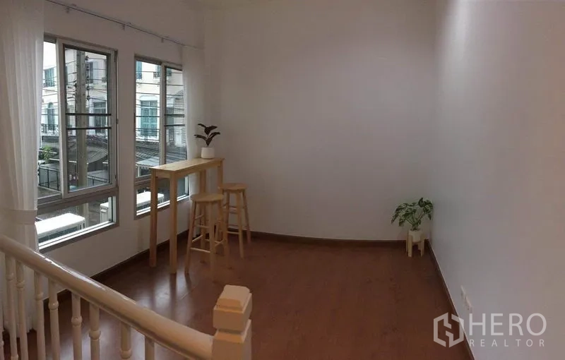 Townhouse for rent in Lat Phrao, Bangkok - Upper-floor landing with corner windows, bar table and indoor plants.