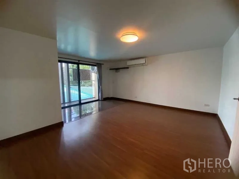 Home Office for rent in Don Mueang, Bangkok - Large bedroom with wood floor and sliding glass door to a balcony.