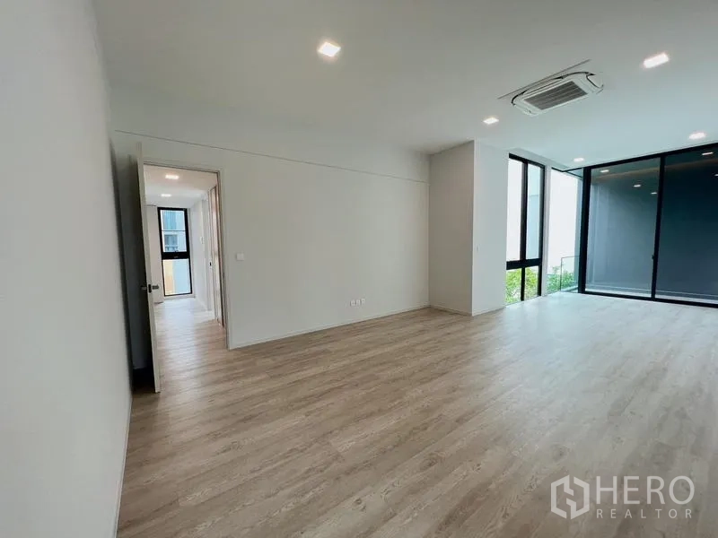 Detached House for rent or sale in Saphan Sung, Bangkok - Large bedroom with wall-to-wall windows and sliding doors to a balcony.