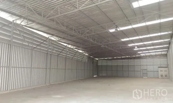 Warehouse for rent in Pathum Thani - Open-plan storage hall with ventilated metal walls and a wide-span roof.