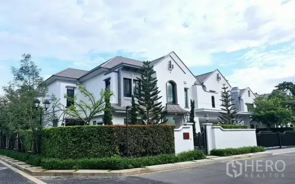 Detached House for rent or sale in Saphan Sung, Bangkok - Street‑facing exterior of the luxury detached home with hedges and gabled roof.