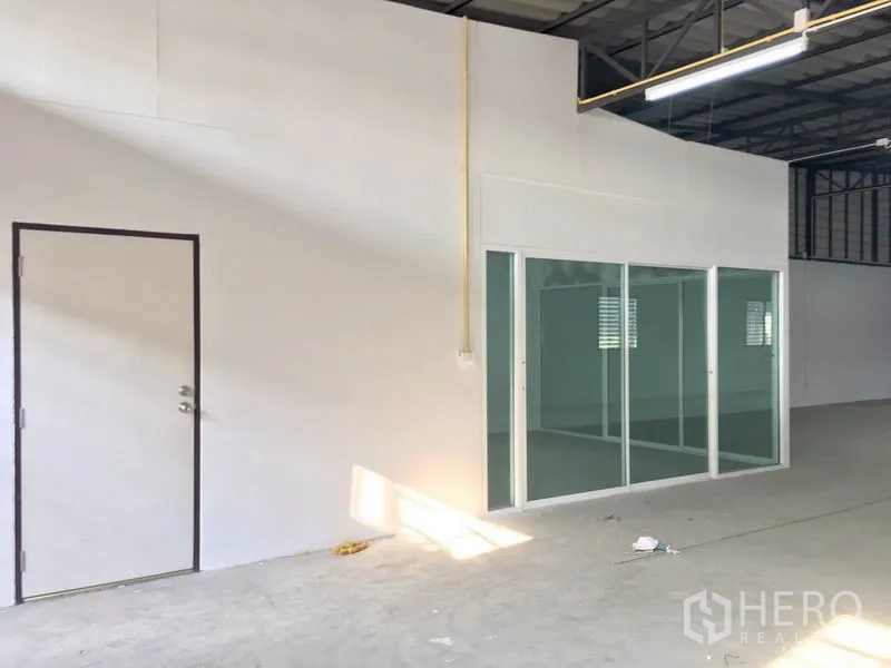 Warehouse for rent in Lam Luk Ka, Pathum Thani - Close-up of the internal office with sliding glass doors and a side service door inside the warehouse.