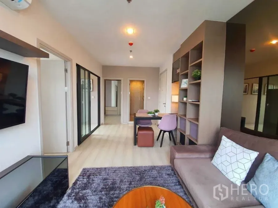 Condominium for sale in Khlong Toei, Bangkok - Open‑plan living and dining area with study nook, light wood floor, and shelving.