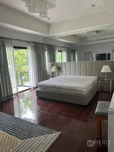 Detached House for sale in Saphan Sung, Bangkok - Spacious master bedroom with balcony doors, mirrored headboard and wood floors.