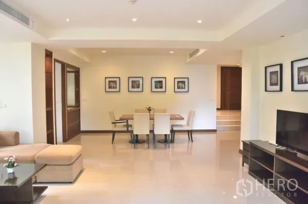 Apartment for rent in Sathon, Bangkok - Spacious lounge facing a six‑seat dining table and framed wall art.