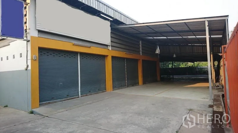 Warehouse for rent in Lak Si, Bangkok - Street-facing warehouse exterior with multiple roller shutter doors and a large covered loading bay.
