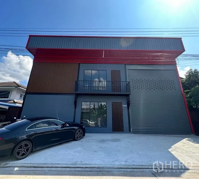 Warehouse for rent or sale in Lam Luk Ka, Pathum Thani - Modern warehouse exterior with balcony, large roller shutter door, and parking apron.