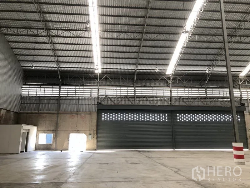 Warehouse for rent in Lam Luk Ka, Pathum Thani - Interior view showing ventilation panels, concrete lower walls and wide shutter doors.