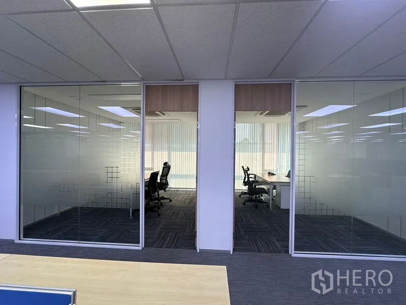 Office Space for rent - View of glass-partitioned offices with frosted panels and carpeted corridor.
