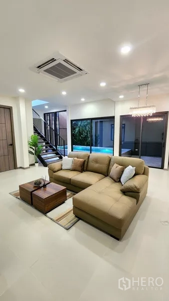 独立式住宅 出售在Khlong Toei, Bangkok - L型沙发的起居区，通向泳池庭院的推拉门。