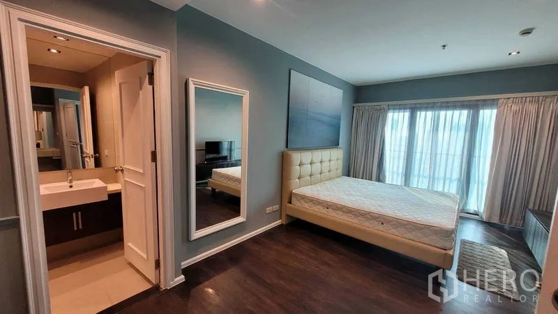 Condominium for rent in Khlong Toei, Bangkok - Master suite with bed, full-length mirror and entrance to the ensuite bathroom with modern basin.