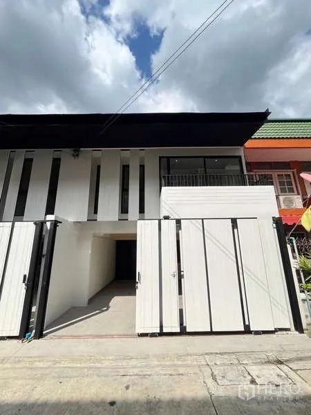 联排别墅 出售在Khlong Toei, Bangkok - 两层现代联排别墅外立面，白色墙面、可停两车的电动门车位与小阳台。