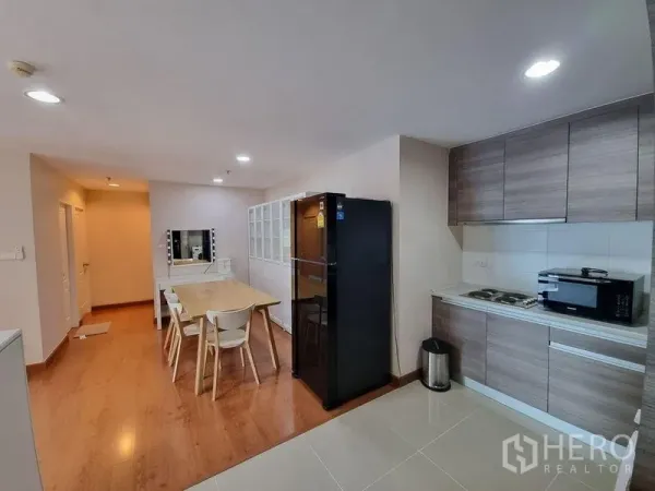公寓 出租在Huai Khwang, Bangkok - 开放式厨房，木纹橱柜、黑色冰箱及用餐区。