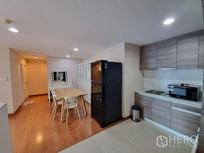 公寓 出租在Huai Khwang, Bangkok - 开放式厨房，木纹橱柜、黑色冰箱及用餐区。