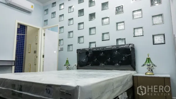 Condominium for rent or sale in Khlong Toei, Bangkok - Master bedroom with tufted headboard, glass‑block accent wall and bedside tables.