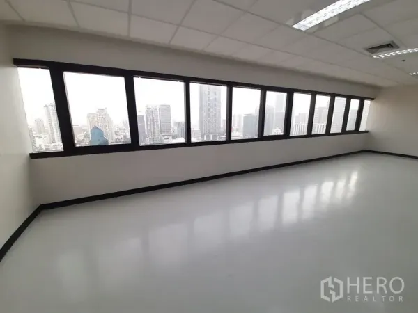 Office Space for rent in Bang Rak, Bangkok - Row of wide windows showcasing a Bangkok skyline view from a bright office corner.