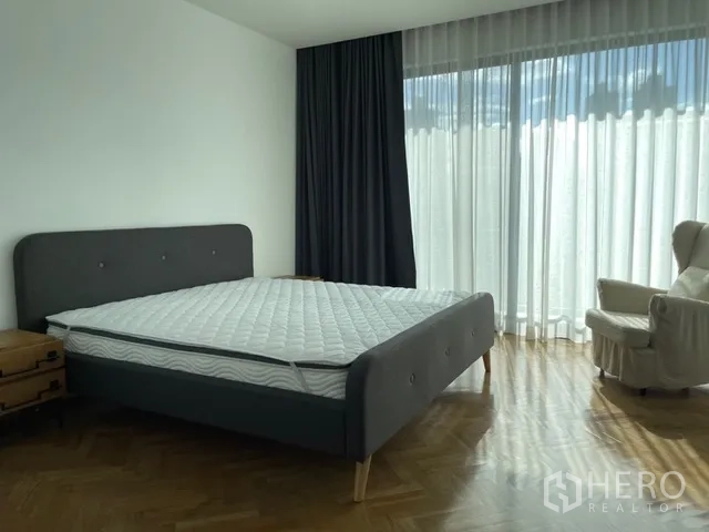 独栋房屋 for rent in Watthana, Bangkok - 主卧配灰色床、扶手椅与长纱帘。
