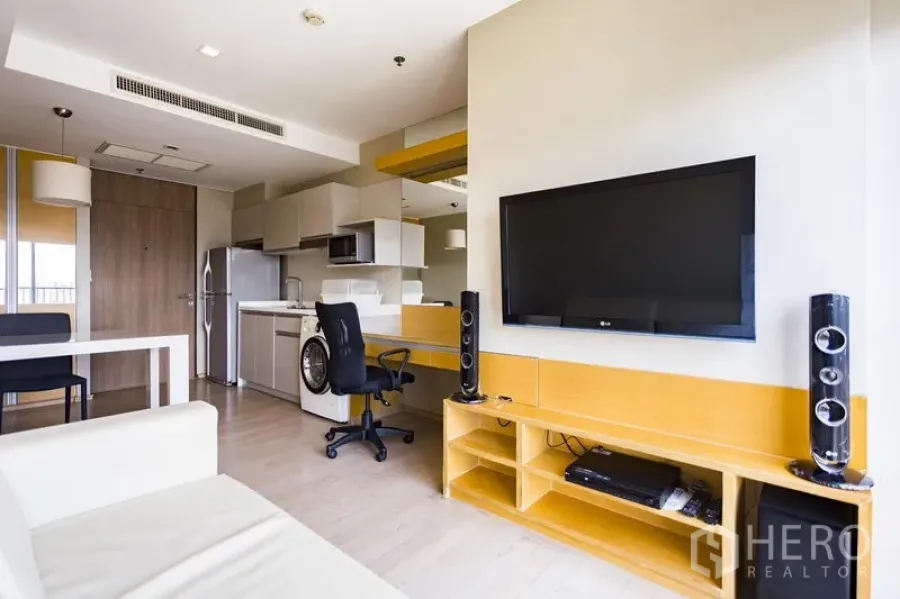 Condominium for rent in Khlong Toei, Bangkok - Open-plan living area at Noble Remix Thong Lo with wall-mounted TV, study desk and media console beside the kitchenette.