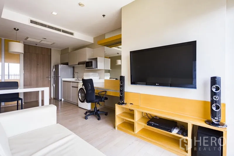 Condominium for rent in Khlong Toei, Bangkok - Open-plan living area at Noble Remix Thong Lo with wall-mounted TV, study desk and media console beside the kitchenette.