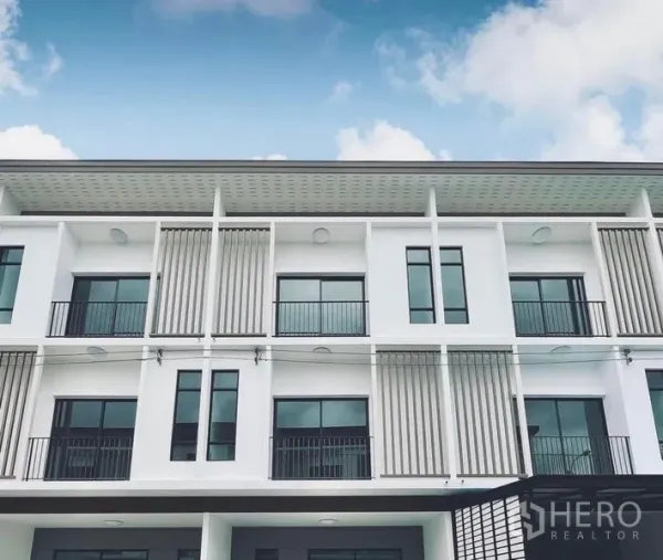 Townhouse for rent in Bang Kapi, Bangkok - Close-up of the modern townhouse exterior showing large windows and metal privacy screens.