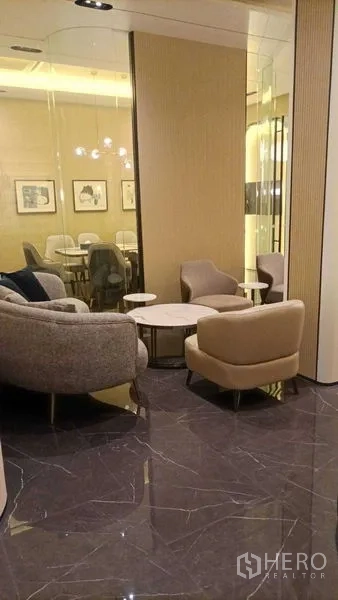 Retail Space for rent - Cozy waiting nook with soft armchairs and round tables beside a glass wall.