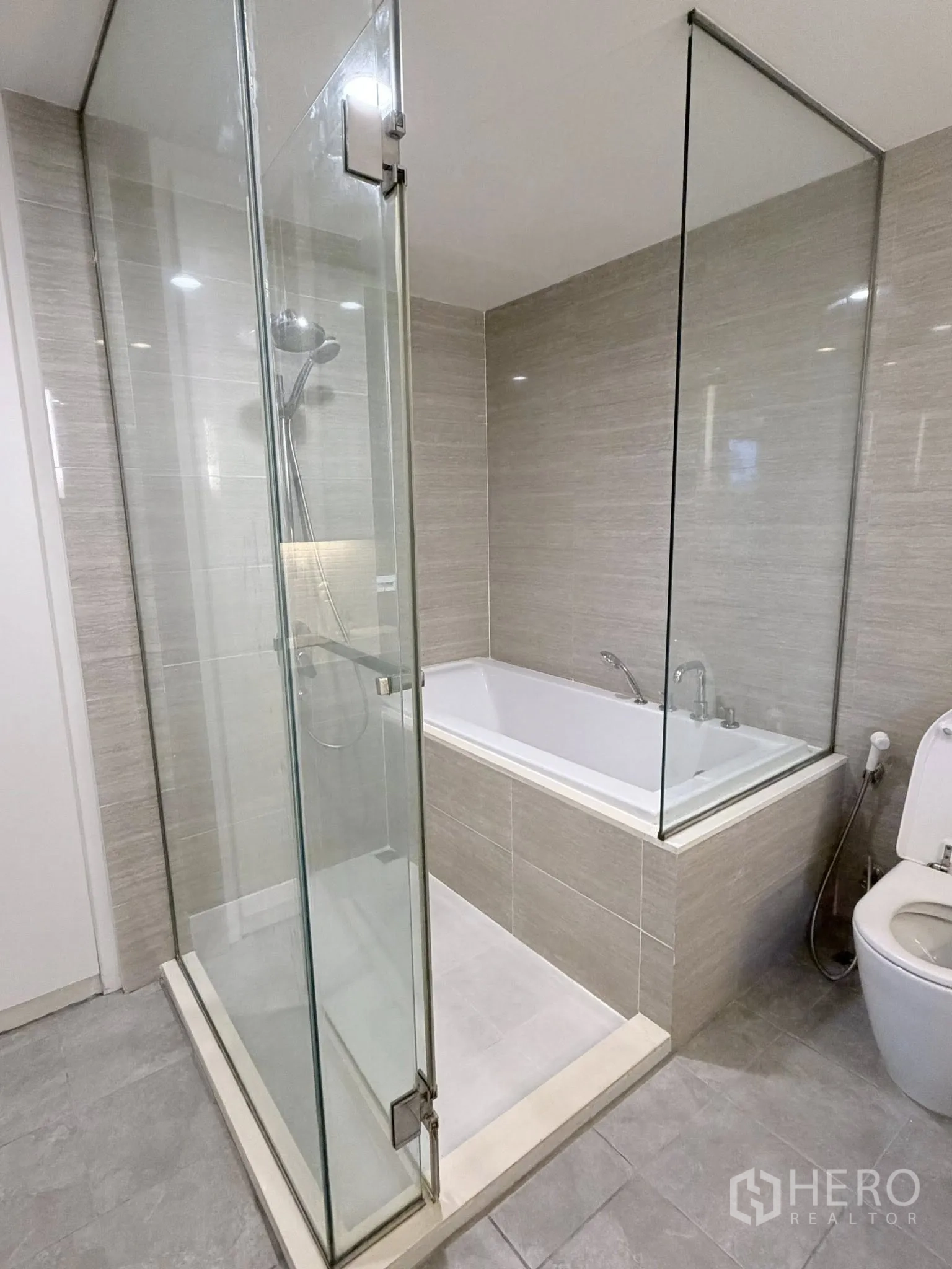 Condominium for rent in Watthana, Bangkok - Modern bathroom with glass-enclosed shower, separate bathtub, and toilet.