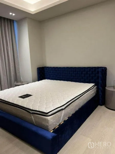 Condominium for rent in Pathum Wan, Bangkok - Primary bedroom with deep blue upholstered bed frame and mattress.