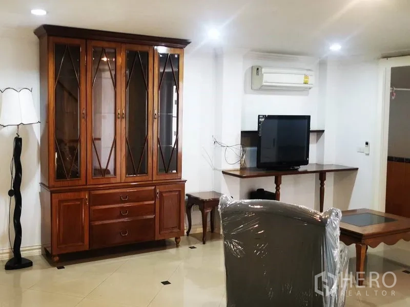 Detached House for rent in Mueang Samut Prakan, Samut Prakan - Cozy living area with a wooden display cabinet, TV and split-type air conditioner.