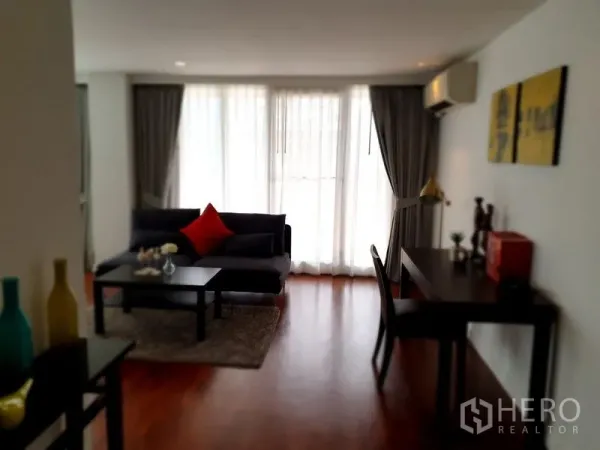 公寓 出租在Bang Rak, Bangkok - 温馨起居一角，沙发、茶几与书桌，靠近整面窗帘墙。