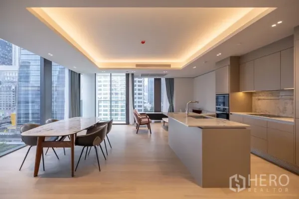 Condominium for rent in Pathum Wan, Bangkok - Wide view of modern kitchen with island and dining beside panoramic glass walls overlooking Bangkok skyline.