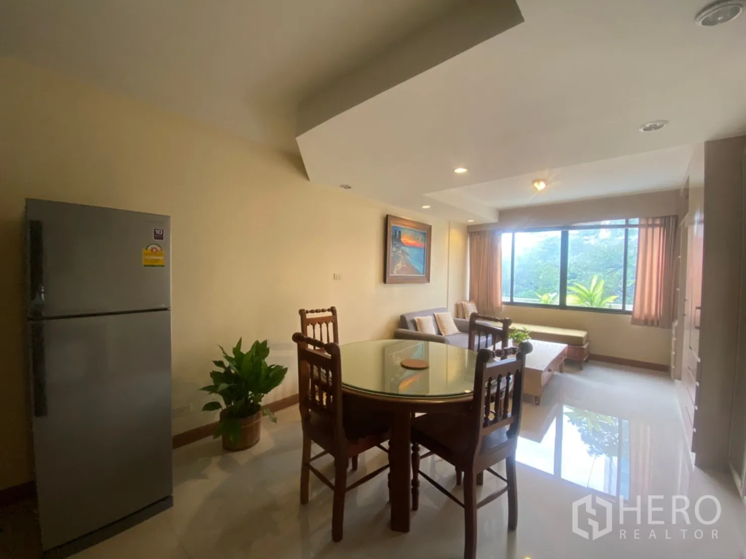 Condominium for rent in Phaya Thai, Bangkok - Dining corner with round glass table facing a wide window and greenery.