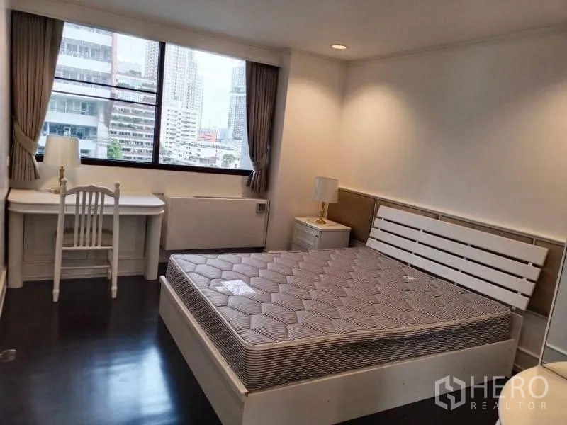 Condominium for rent in Sathon, Bangkok - Second bedroom with a writing desk by the window and a city skyline outlook.