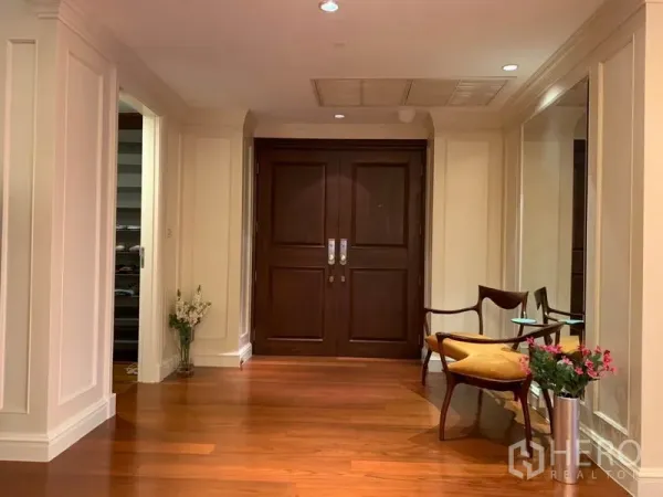Condominium for rent or sale in Watthana, Bangkok - Elegant foyer featuring double wooden doors, a bench seat and wall mirror.