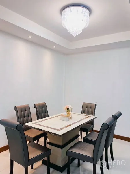 Townhouse for rent in Huai Khwang, Bangkok - Six-seat dining set under a modern chandelier in a clean white room.