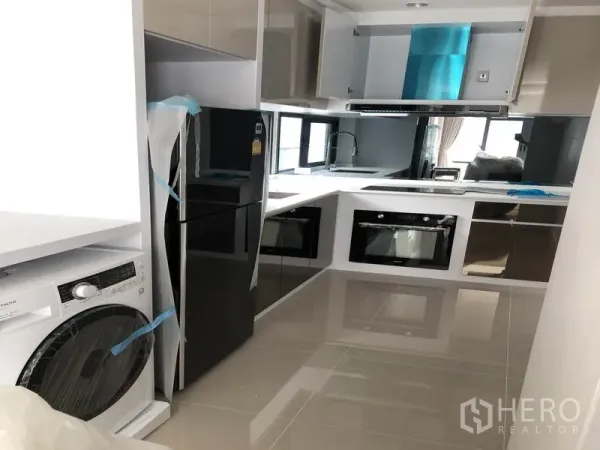 Detached House for rent in Prawet, Bangkok - U-shaped modern kitchen with glossy cabinets, built-in oven, refrigerator and washing machine.