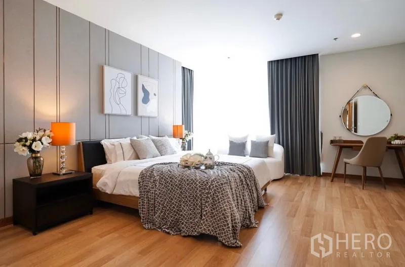 公寓 出租在Watthana, Bangkok - 宽敞主卧套房，带休闲沙发、梳妆台与现代装饰。
