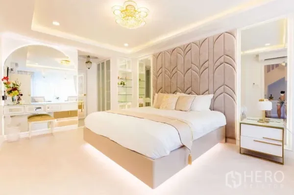 Townhouse for rent in Lat Phrao, Bangkok - Spacious bedroom with padded feature wall, underlit platform bed and built-in mirrored wardrobes and vanity.