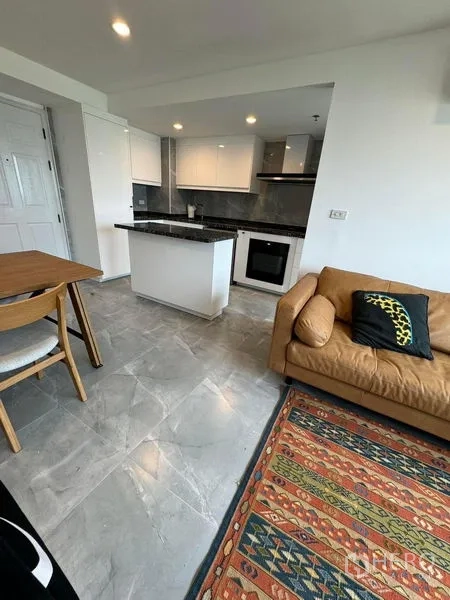 Condominium for rent or sale - Modern kitchen with white cabinetry, black granite countertop island, and built-in oven.