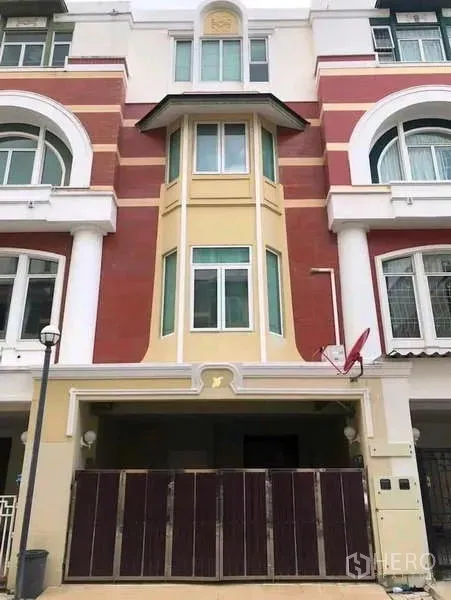 Townhouse for rent in Phra Khanong, Bangkok - Four-storey townhouse facade in red and cream with gated carport in Phra Khanong.