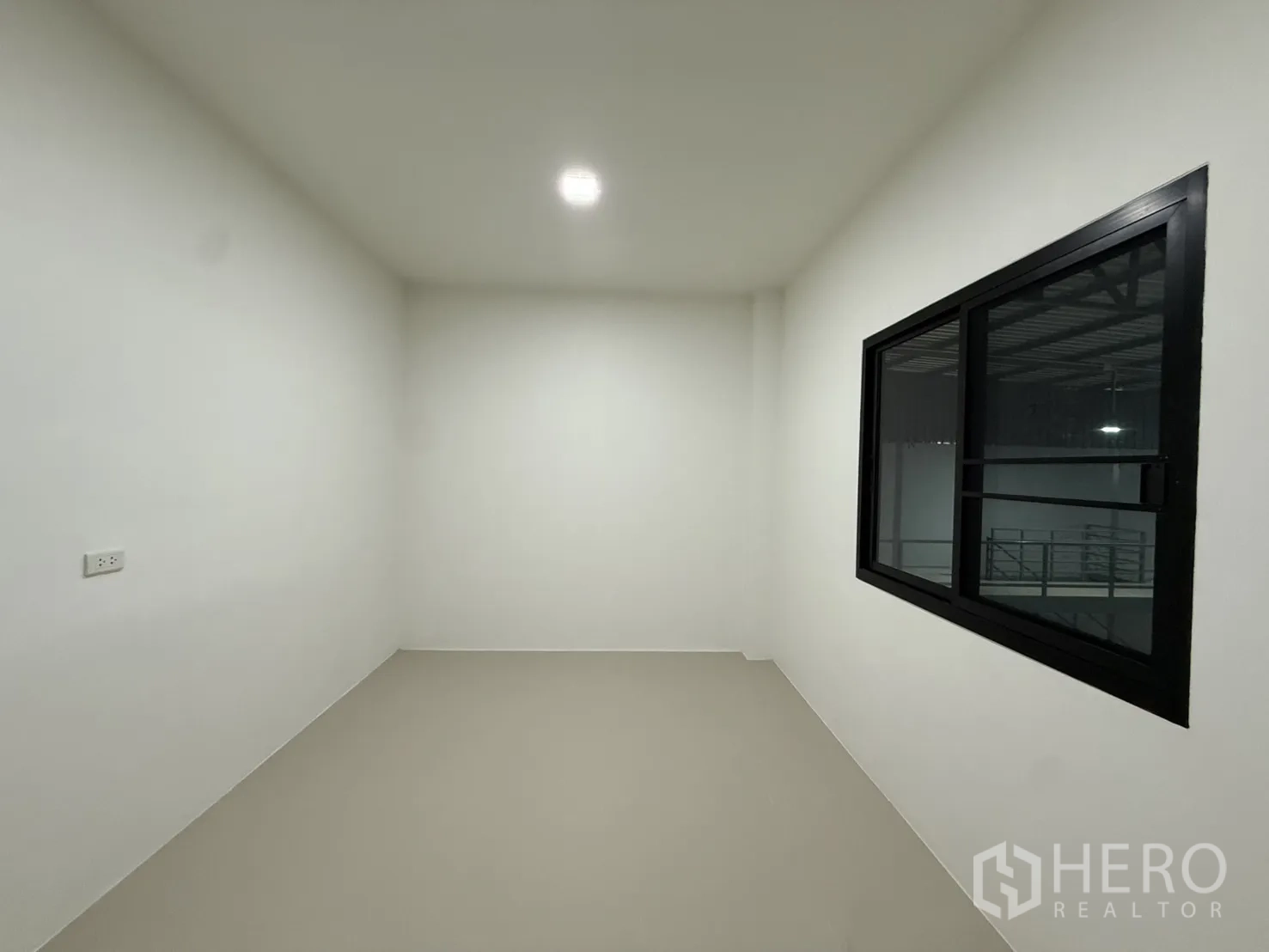Warehouse for rent in Lam Luk Ka, Pathum Thani - Empty office room with internal viewing window to the warehouse.