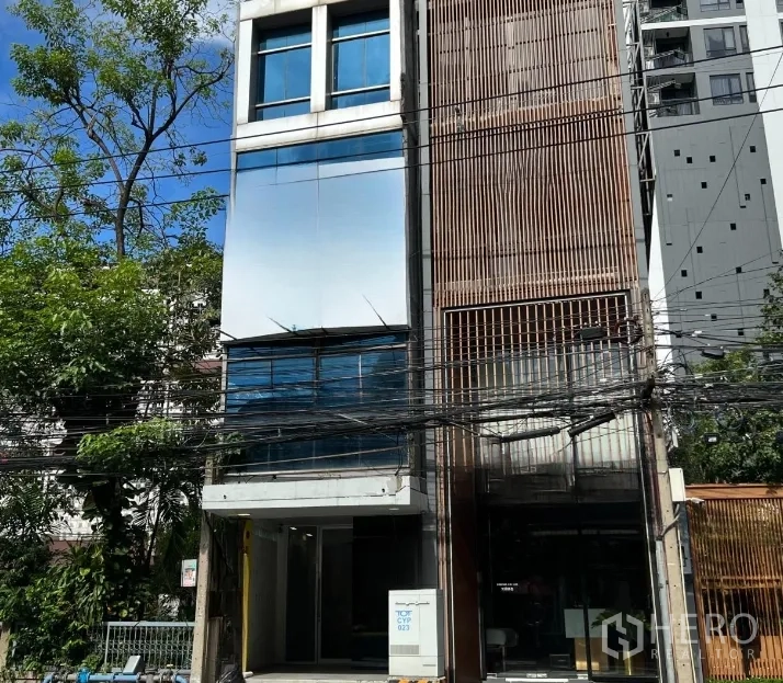 พื้นที่ขายปลีก ให้เช่าในWatthana, Bangkok - อาคารชอปเฮาส์สูง 4 ชั้น ด้านหน้าเป็นกระจกและระแนงไม้ มีต้นไม้และสายไฟด้านหน้า