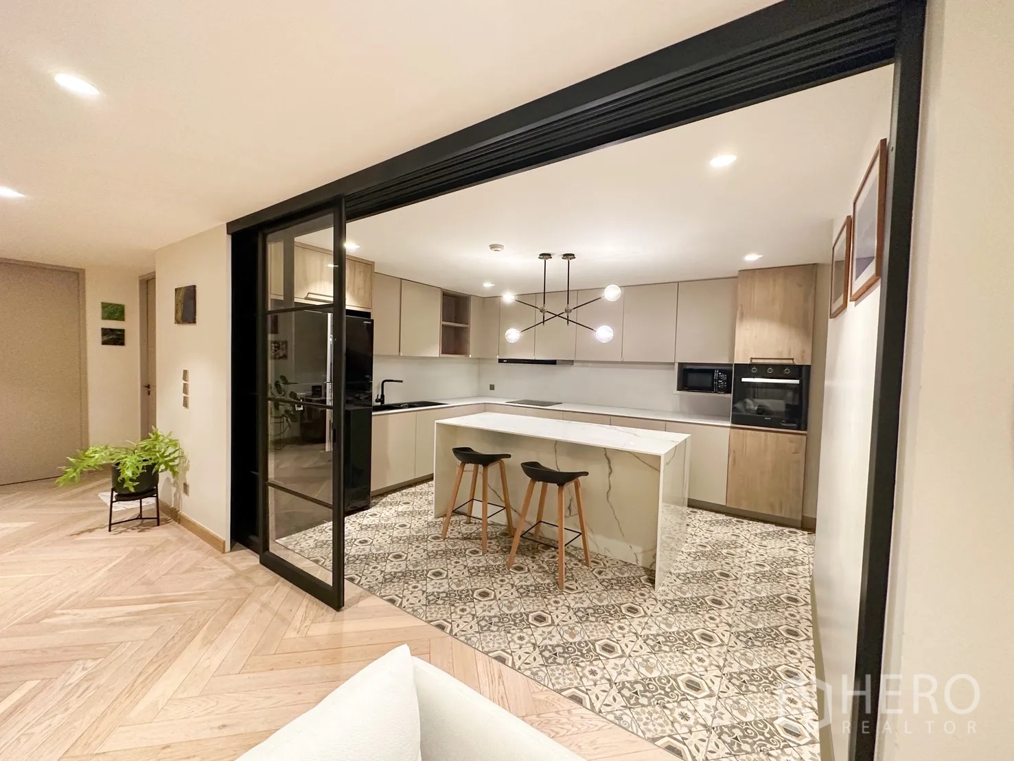 Condominium for rent or sale in Watthana, Bangkok - Contemporary kitchen with island, bar stools, and a sliding glass partition.