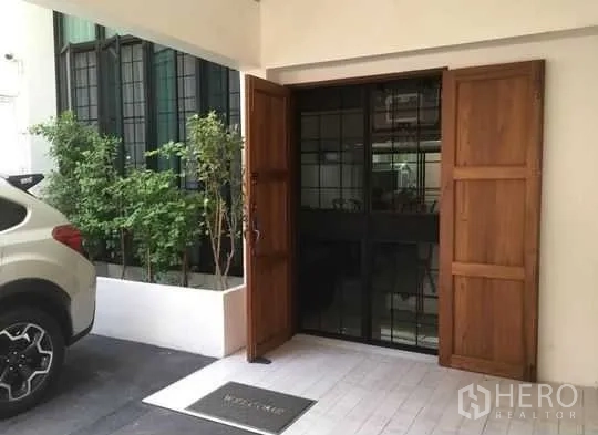 联排别墅 出租在Bang Rak, Bangkok - 带顶车位与入户区，木质双开门和黑色金属大门。
